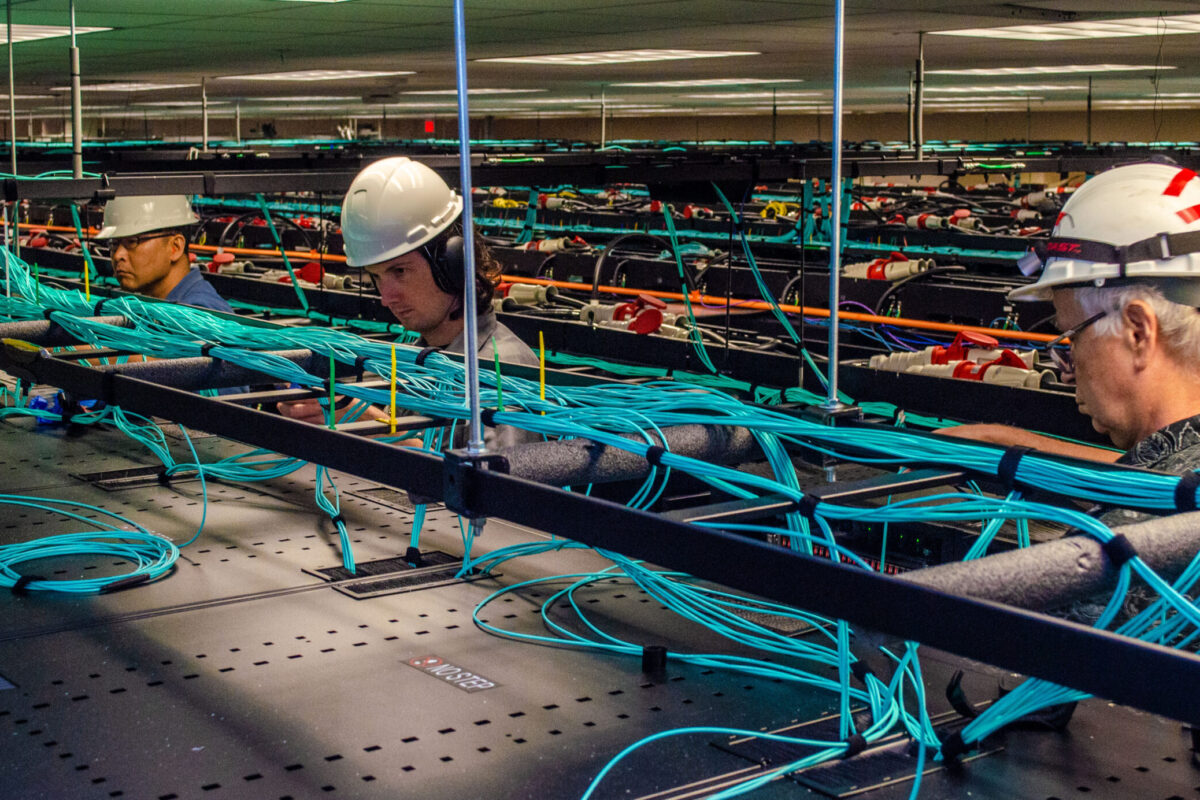 TACC employees work on the network cabling above the racks of Frontera. 