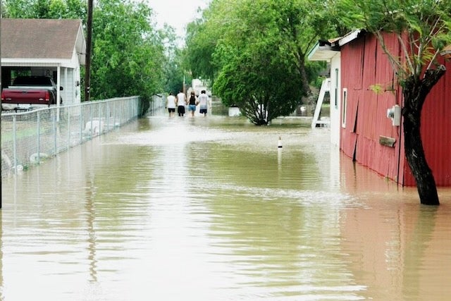 family walks home through flood waters