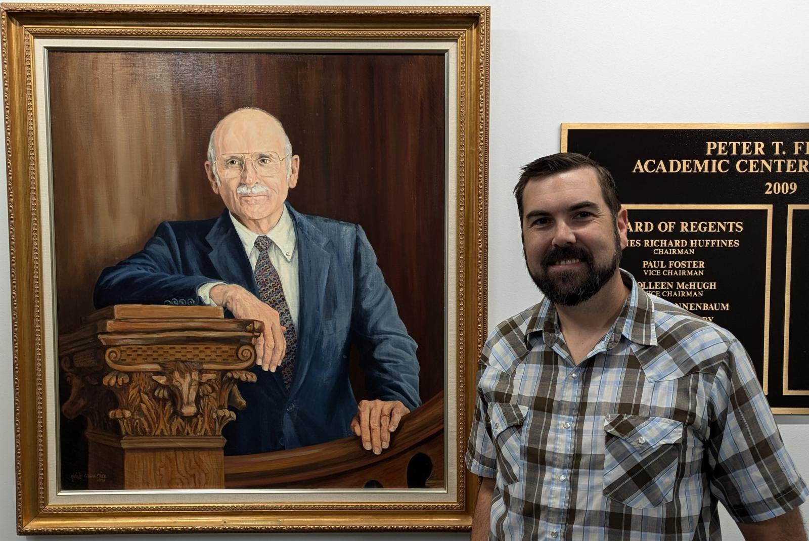 Jason Watson standing next to the portrait of Pete Flawn, the namesake of the Flawn Academic Center.