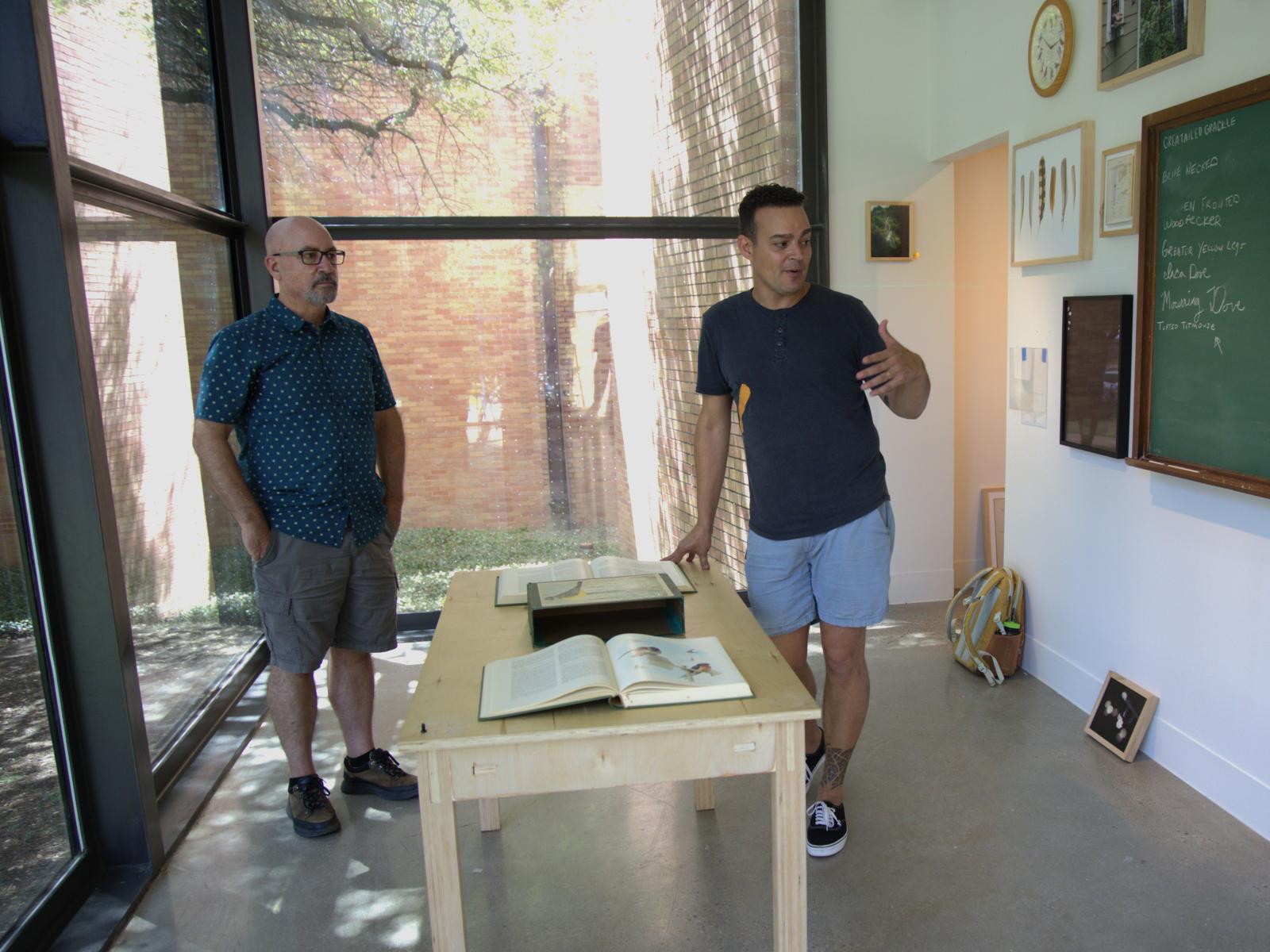 Integrative biology professor Tim Keitt (left) and artist Mark Menjívar discuss Menjívar’s installation in August, before the exhibition opened. Research on birds by Keitt and one of his graduate students, Brian Stokes, inspired and informed Menjívar’s work. 